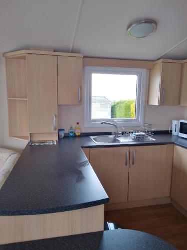 a small kitchen with a sink and a window at Ocean Heights 5 star site NewQuay in Llanllwchaiarn