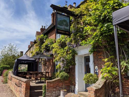 a brick house with a sign on the side of it at Cowpers Oak in Olney