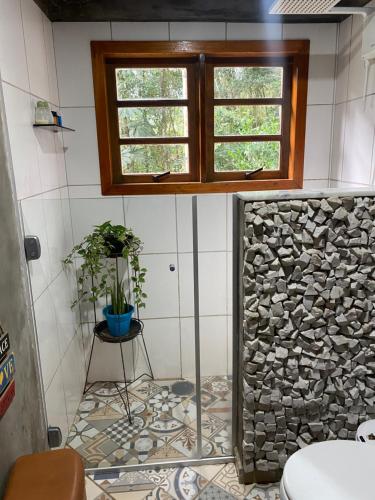 baño con ventana y pared de piedra en Casa de campo com muito verde e paz/2 quartos/Wi-Fi/churrasqueira/ deck/ trilha/ minha cachoeira en Rio Acima
