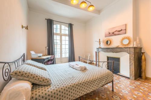 a bedroom with a bed and a fireplace at L'Authentique - Central - Spacieux - WiFi - Parking Prox in Pézenas
