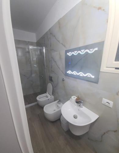a white bathroom with a sink and a toilet at Hotel Noel in Vlorë