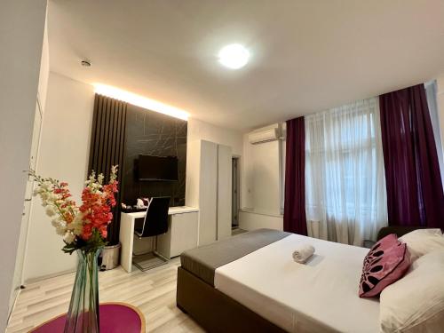 a hotel room with a bed and a vase of flowers at Centar Forever in Belgrade