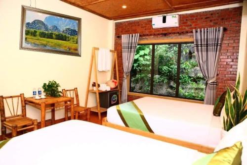 1 dormitorio con 2 camas, mesa y ventana en Tam Coc Valley Homestay, en Ninh Binh