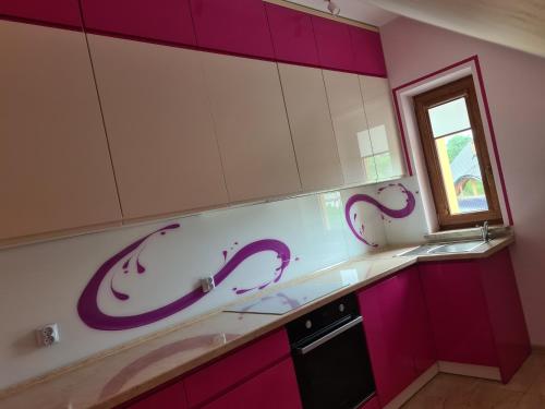une cuisine avec des placards violets et blancs et une fenêtre dans l'établissement MARMI Noclegi, à Golczowice