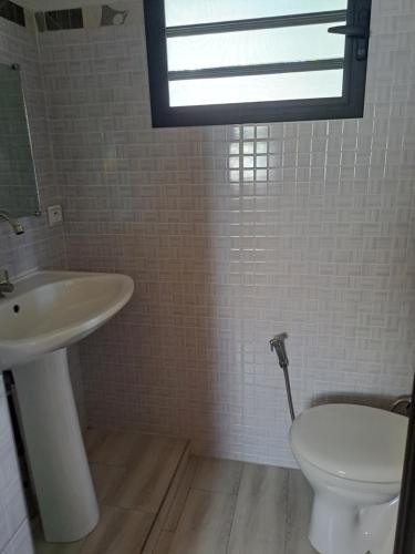 a bathroom with a sink and a toilet and a window at le tamarin in Toliara