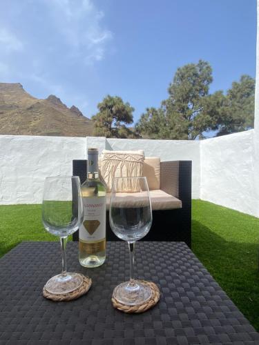 una botella de vino y dos copas de vino en una mesa en Villa LA RAMA DEL DRAGO, Agaete, en San Pedro
