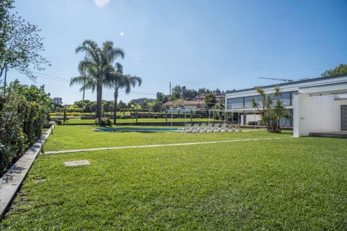 a yard with a building and palm trees at Quinta Do Pomar Pomar Farm in Linhares