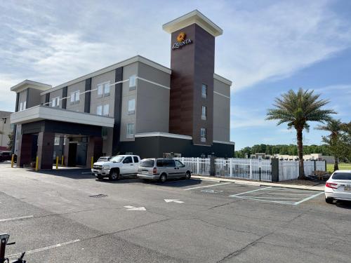 a building with two cars parked in a parking lot at La Quinta by Wyndham Gonzales LA in Gonzales