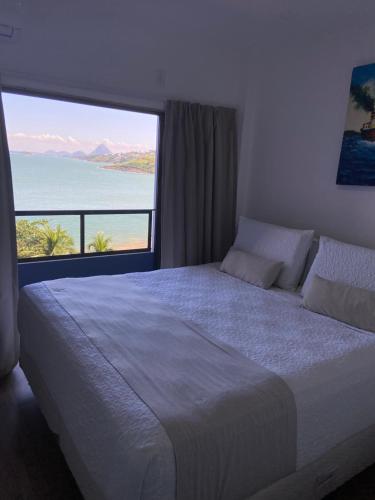 a bedroom with a large bed with a large window at Hotel Espadarte in Iriri