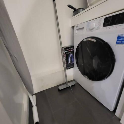 a washing machine in a kitchen with a pole next to it at Beautiful Brighton Apartment, 5min walk to beach in Brighton & Hove
