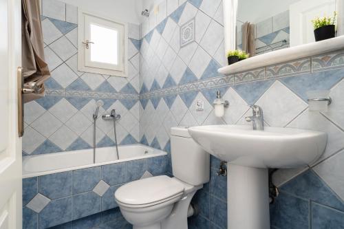 a blue and white bathroom with a toilet and a sink at Erato Inn Naxos in Agios Prokopios