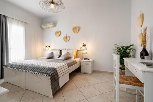 a white bedroom with a bed and a desk at Erato Inn Naxos in Agios Prokopios