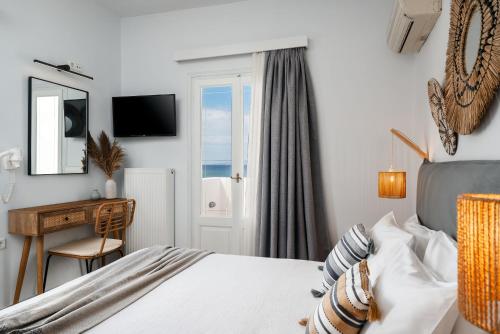 a bedroom with a bed and a desk and a window at Erato Inn Naxos in Agios Prokopios