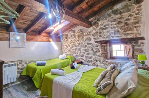 1 dormitorio con 2 camas verdes en una pared de piedra en La Cantina casas rurales paredes en Villar de Corneja
