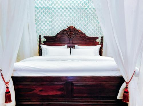 a bedroom with a wooden bed with white curtains at Angirasa Luxury Camping in Hyderabad