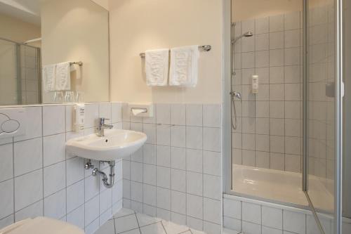 a white bathroom with a sink and a shower at SANDnature in Timmendorfer Strand