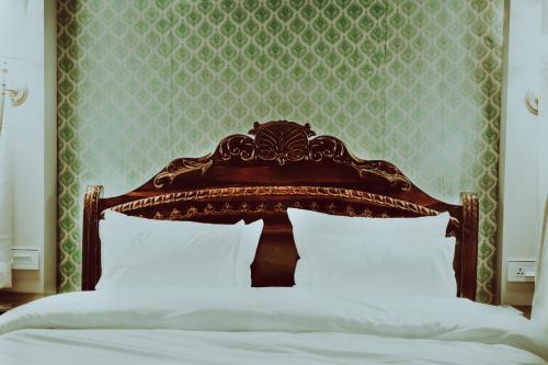 a bed with a wooden headboard and white sheets at Angirasa Luxury Camping in Hyderabad