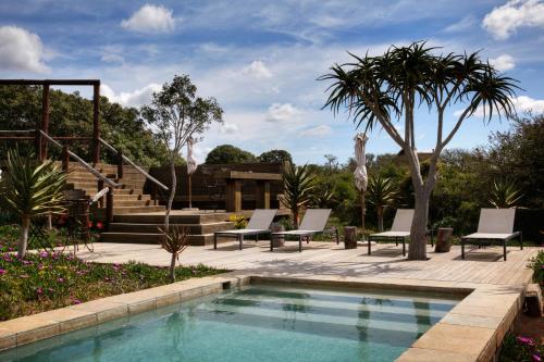 a swimming pool with lounge chairs and a house at Bush Lodge – Amakhala Game Reserve in Amakhala Game Reserve