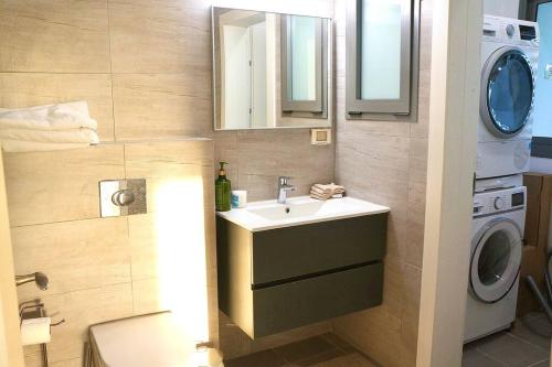 y baño con lavabo y lavadora. en Brand New Flat Seaview 4BDR 140m2, en Netanya