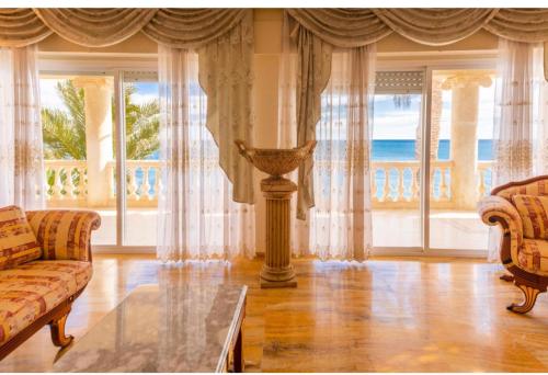 un soggiorno con divano, tavolo e finestre di Villa (Palace) Unique avec plage privée a Santa Faz