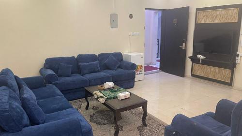 - un salon avec des canapés bleus et une table basse dans l'établissement مسكن راحتك للشقق المخدومه, à Tabuk