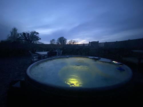 a hot tub in a yard at night at Peibio at Llanfair Hall in Dwyran