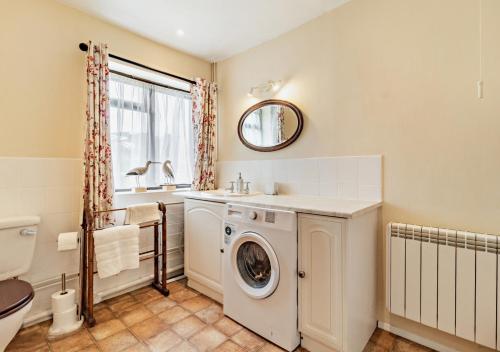 een badkamer met een wasmachine en een wastafel bij The White Horse Cottage in Saint James