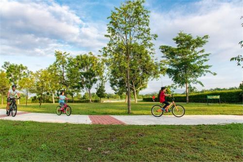 three people riding bikes on a path in a park at Bougainvillea Botani Home in Ipoh