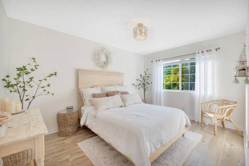 - une chambre blanche avec un lit, une table et une fenêtre dans l'établissement Conejo Oasis, à Thousand Oaks