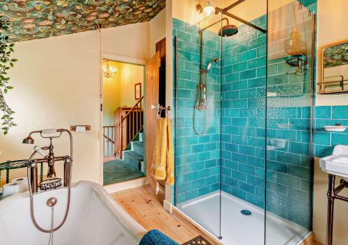 a bathroom with a tub and a shower with blue tiles at Town Cottage in Halesworth