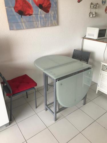 un tavolo in vetro e una sedia in una stanza di Studio Cala Sognu Moriani residence a San-Nicolao