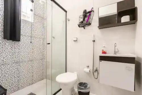 a bathroom with a toilet and a glass shower at Pousada Casa da Fernanda, Suíte Family in Praia Grande