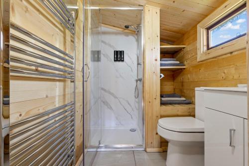 a bathroom with a shower and a toilet at Choller Lake Lodges - Sunbeam Cabin With Private Hot Tub in Arundel