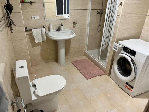 a bathroom with a toilet sink and a washing machine at Casa Brisa del mar in Puerto de Sagunto