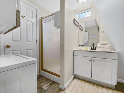 W białej łazience znajduje się umywalka i lustro. w obiekcie Woodchuck Cabin w mieście Duck Creek Village