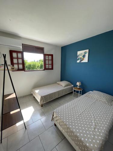 a bedroom with two beds and a blue wall at Gîtes Mon Trésor in Anse-Bertrand