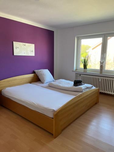 a bedroom with a wooden bed with a purple wall at Apartment Geronimo in Werne an der Lippe