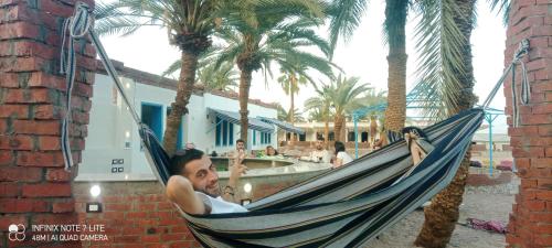 a man laying in a hammock on the beach at Palm Valley camp in Nuweiba‘ el Muzeinah