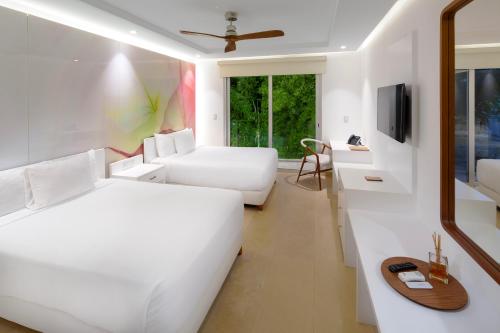 Habitación blanca con 2 camas y sofá en Antera Hotel & Residences, en Playa del Carmen