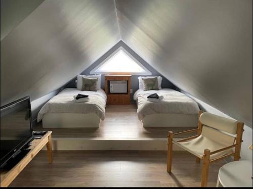een slaapkamer op zolder met 2 bedden en een televisie bij Tremblant Village Retreat!Steps to hill & trails in Mont-Tremblant