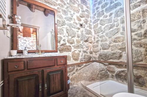 un bagno in pietra con lavandino e specchio di casa rural La Fragua a Villar de Corneja