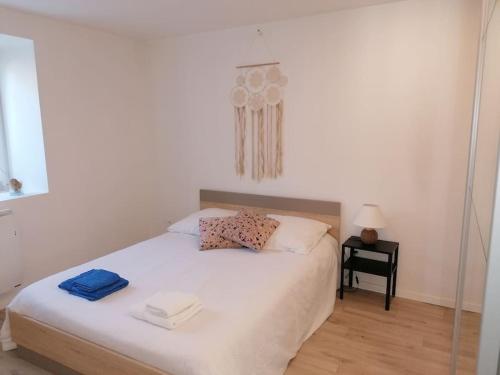 1 dormitorio con 1 cama blanca y 2 toallas en Appartement cosy au calme La Salamandre, 