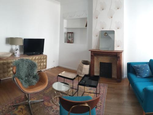 sala de estar con sofá azul y chimenea en Flut'Alors - Maison charmante au centre-ville de Reims, en Reims