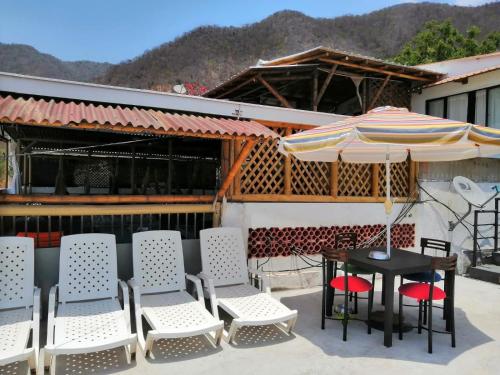 einen Tisch, Stühle und einen Regenschirm auf einer Terrasse in der Unterkunft Casa Italia Guest House in Taganga