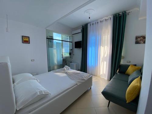 een slaapkamer met een bed, een bank en een raam bij Hotel Kristal Borsh in Borsh