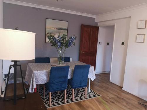 une table à manger avec des chaises bleues et un vase de fleurs dans l'établissement 2 bed flat, Bounds Green, Piccadilly line, London N11, à Londres