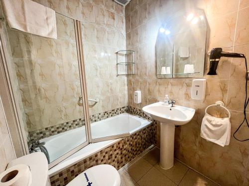 a bathroom with a toilet a sink and a bath tub at Hacienda Guadalquivir in Córdoba