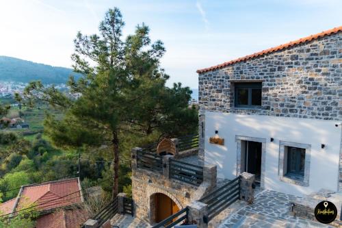 a stone building with stairs next to a tree at Pinolia Rooms in Chios