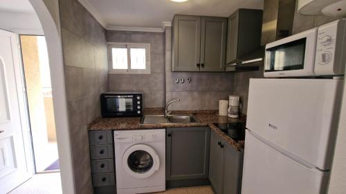 a small kitchen with a washing machine and a microwave at Lovely one bedroom unit with balcony and pool in Denia