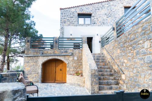 a stone building with a wooden door and stairs at Pinolia Rooms in Chios